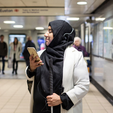 A person navigating an airport by listening to the instructions on a mobile phone.